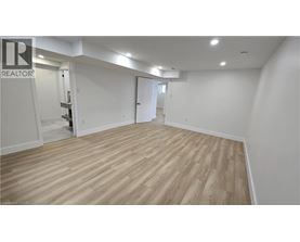 A spacious room with wooden flooring and white walls.
