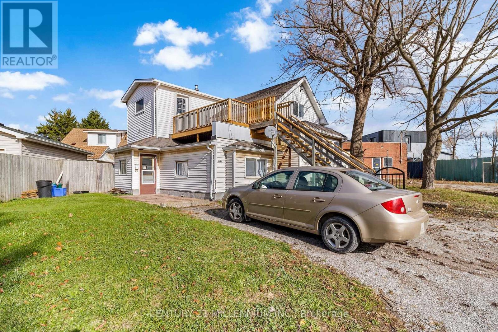 A car is parked in front of a house with a brown roof.