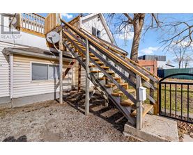 A wooden staircase with a metal railing leads up to a balcony.