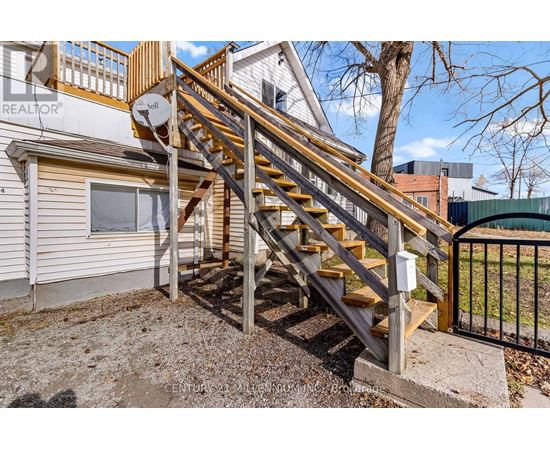 A wooden staircase with a metal railing leads up to a balcony.