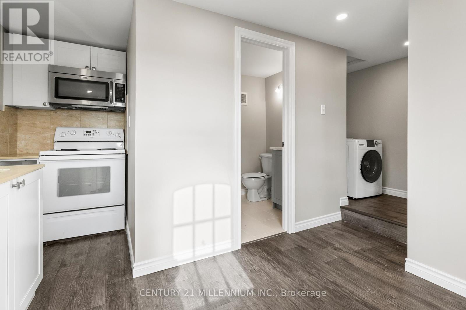 A kitchen with a microwave, oven, and a washing machine.