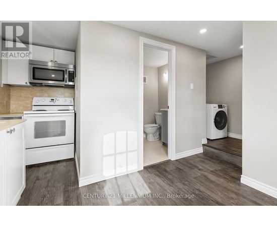 A kitchen with a microwave, oven, and a washing machine.