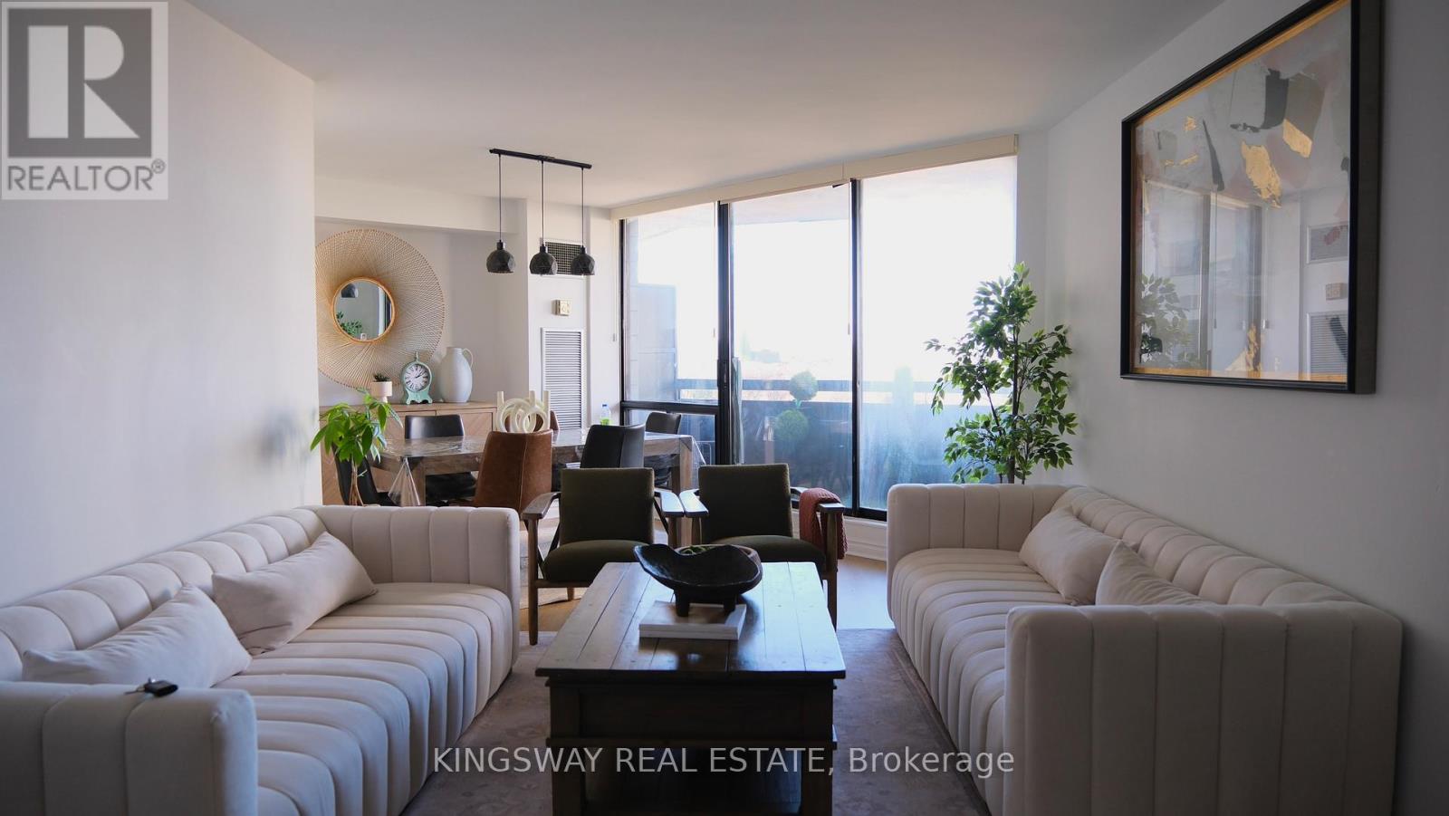 A living room with a couch, chairs, and a table with a plant on it.