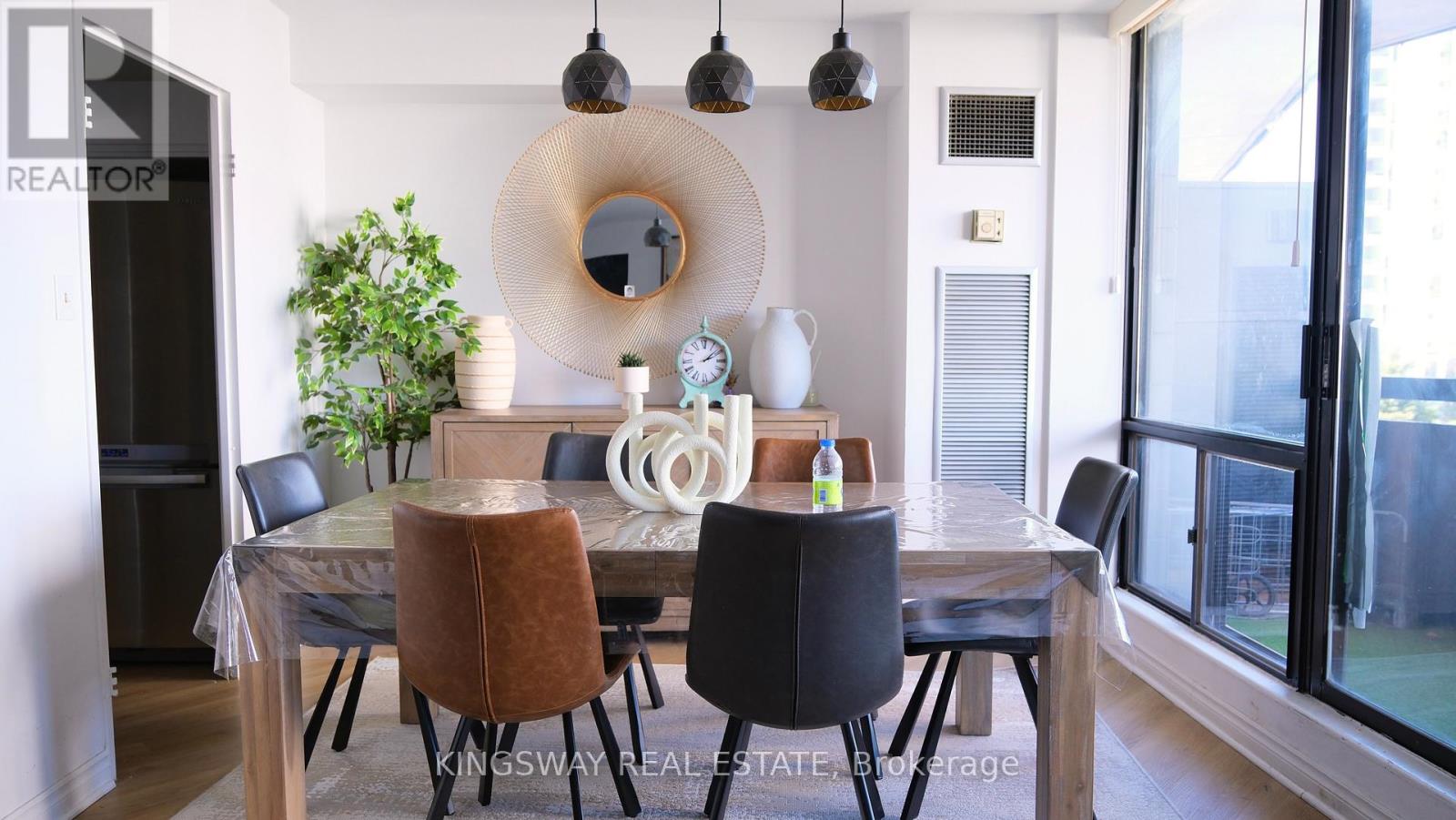 A dining room with a table set for four and a plant on the side.