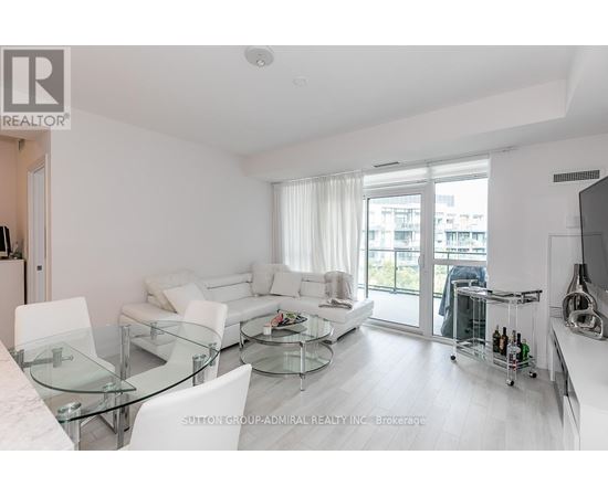 A modern living room with a glass table and white furniture.