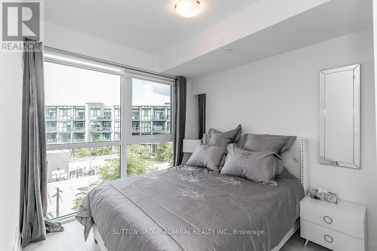 A bedroom with a large bed and a view of a cityscape through the window.