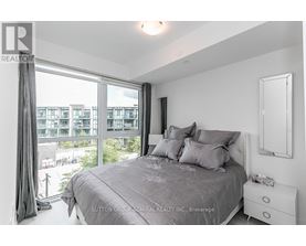 A bedroom with a large bed and a view of a cityscape through the window.