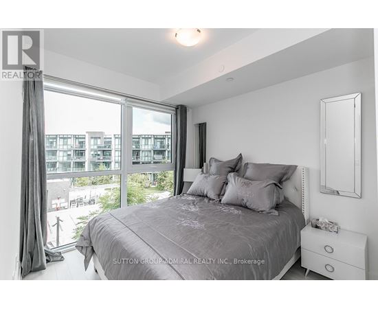 A bedroom with a large bed and a view of a cityscape through the window.