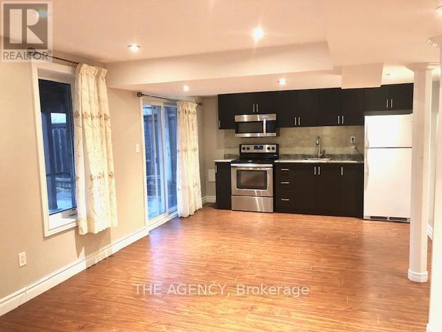 A kitchen with black cabinets and a white refrigerator.