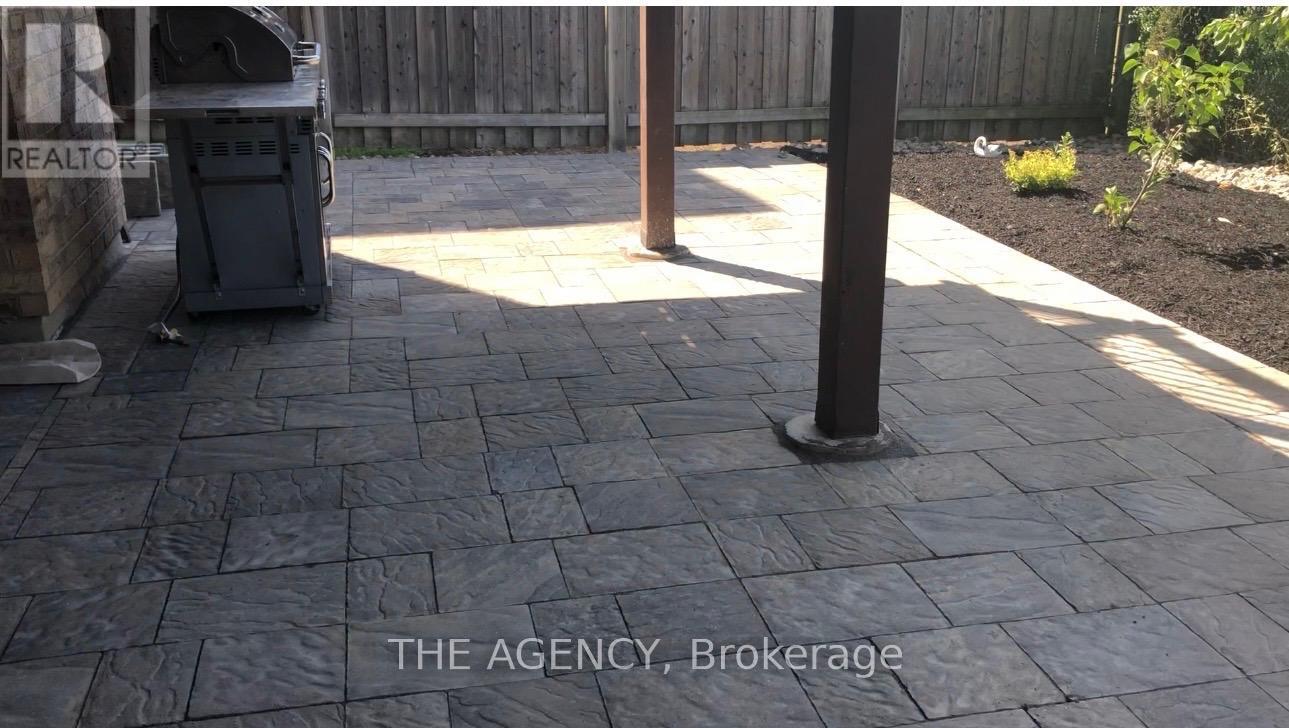 A patio with a black trash bin and a wooden fence.