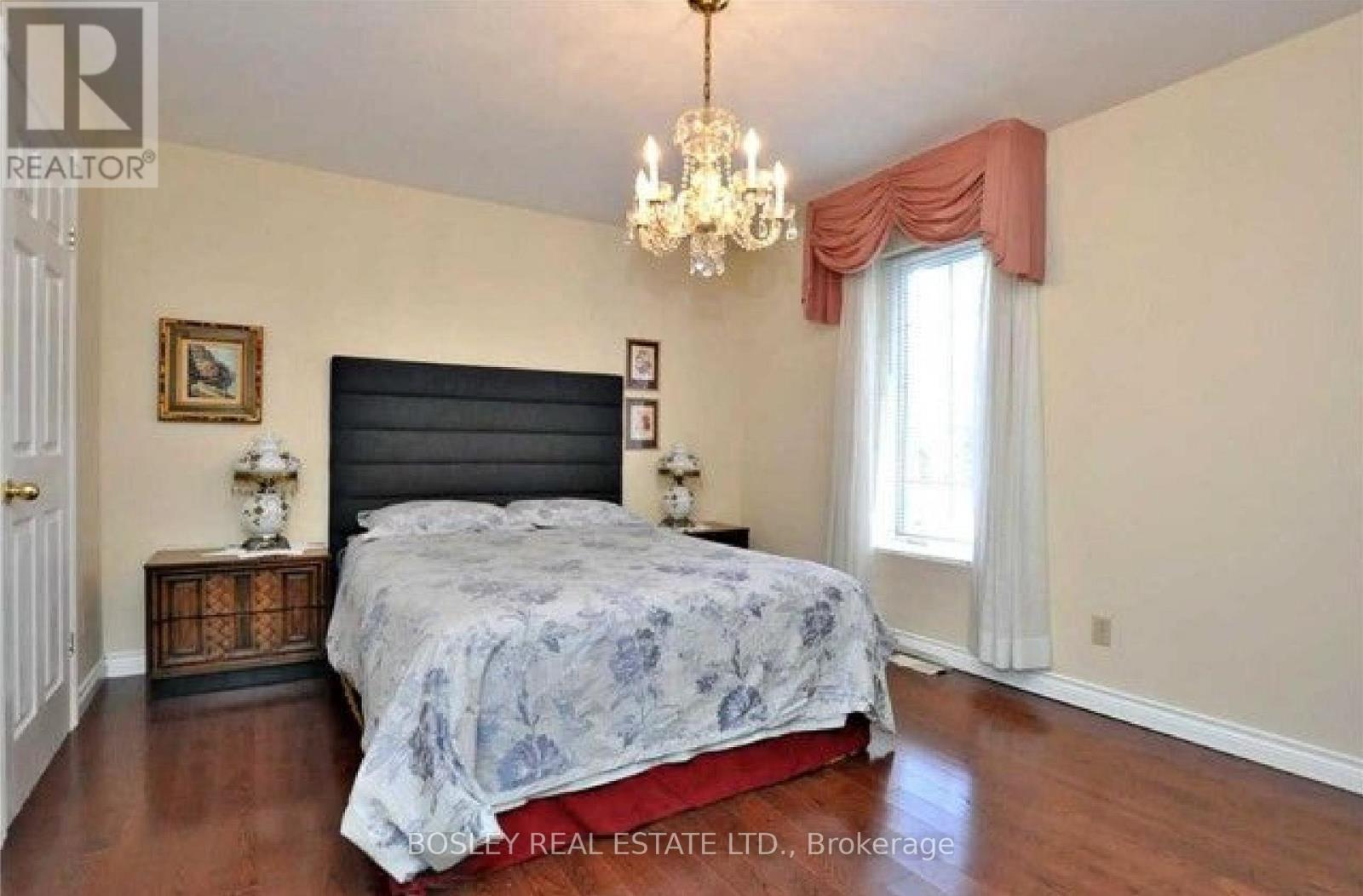 A bedroom with a large bed and a chandelier.