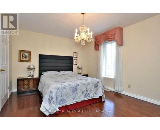 A bedroom with a large bed and a chandelier.