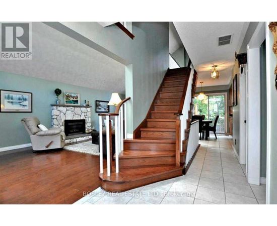 A living room with a fireplace and a staircase.