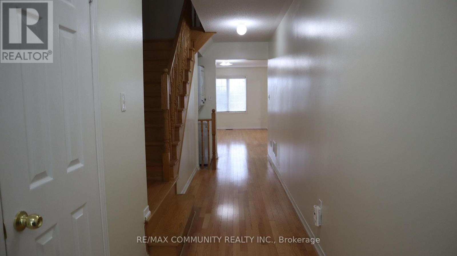 A hallway with a door on the left and a staircase on the right.