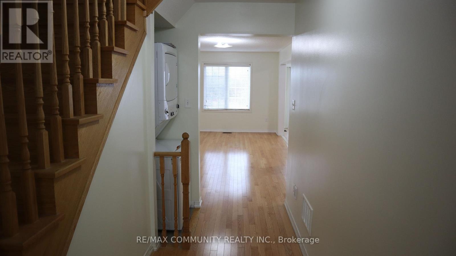 A hallway with a staircase on the left and a door on the right.