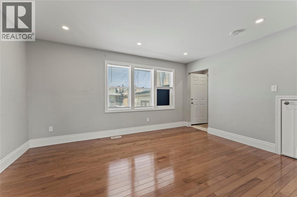 A spacious room with wooden flooring and a large window.