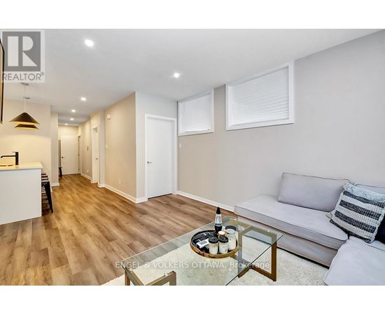 A living room with a glass coffee table and a grey couch.