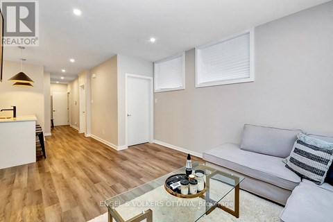 A living room with a glass coffee table and a grey couch.