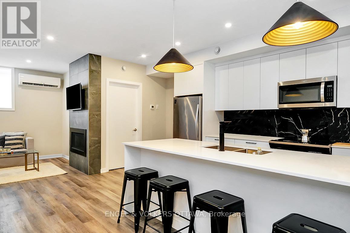 A modern kitchen with a bar stool and a microwave above the counter.