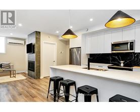 A modern kitchen with a bar stool and a microwave above the counter.