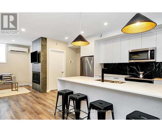 A modern kitchen with a bar stool and a microwave above the counter.