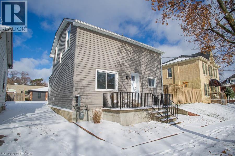 A house with a grey siding and a black railing is surrounded by snow.