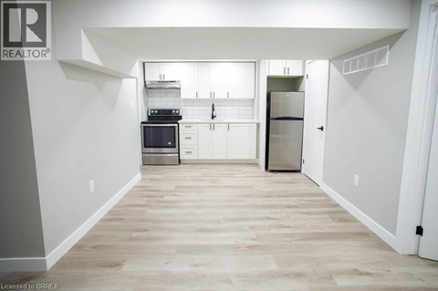 A kitchen with white cabinets and a wooden floor.