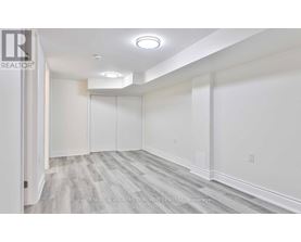 A spacious room with white walls and grey flooring.