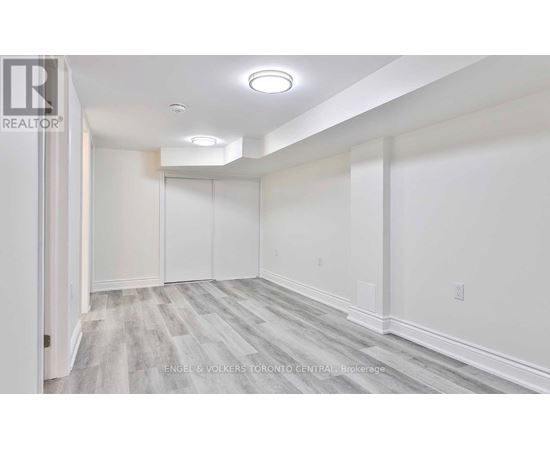 A spacious room with white walls and grey flooring.