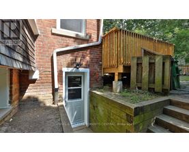 A wooden structure with a door is in front of a brick building.