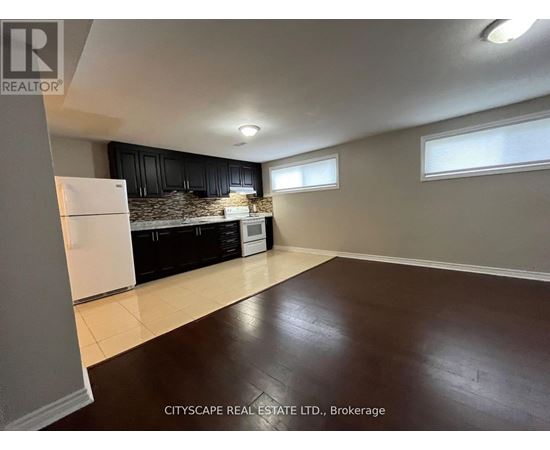 A kitchen with black cabinets and a white fridge is shown.