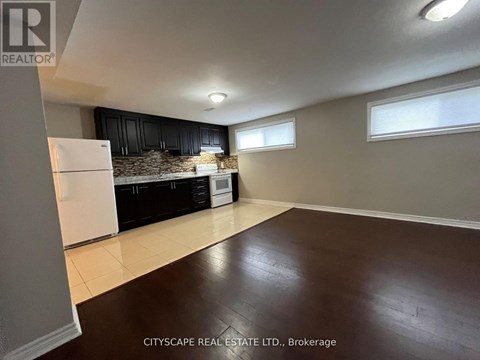 A kitchen with black cabinets and a white fridge is shown.