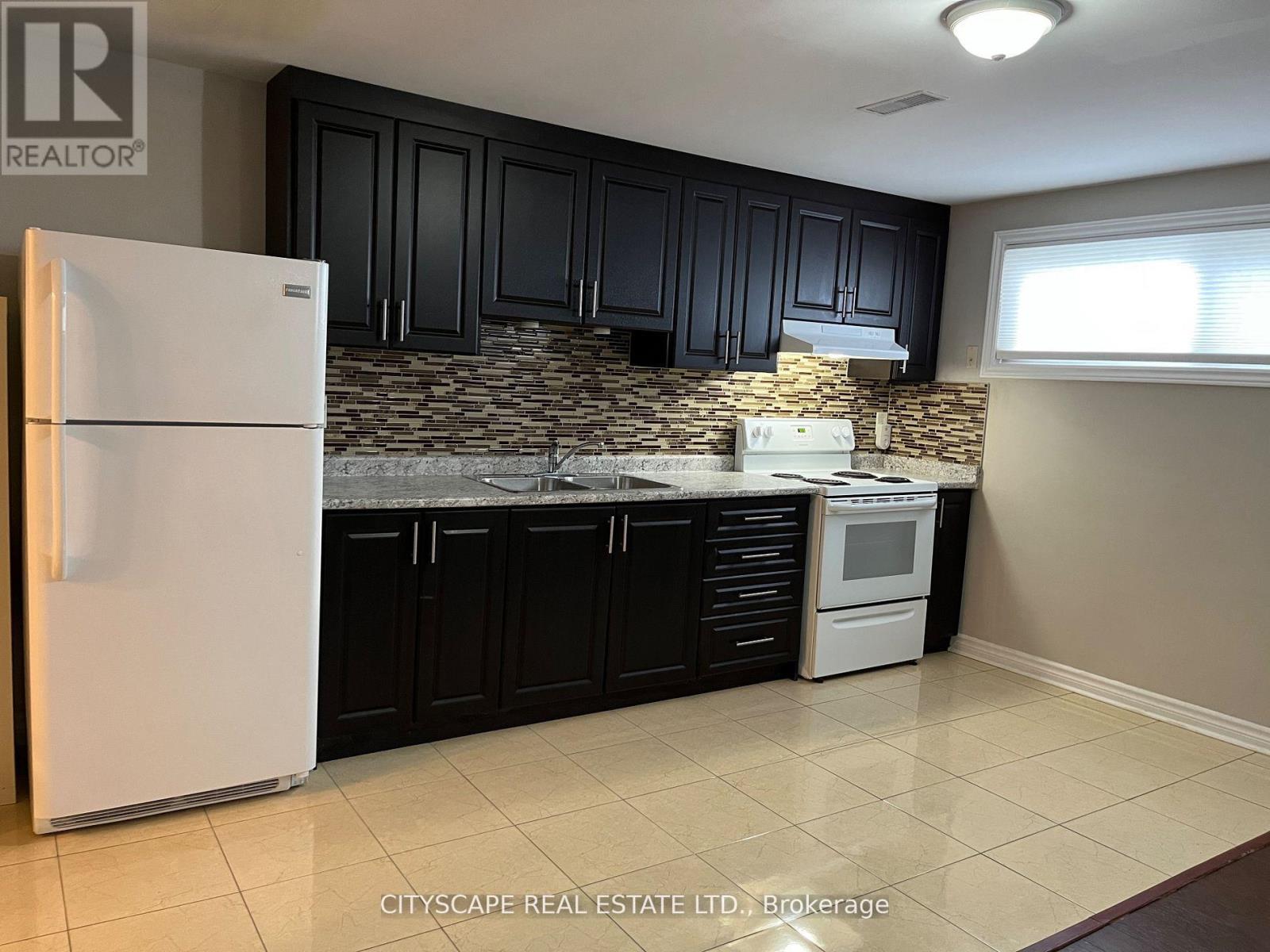 A kitchen with a white fridge and black cabinets.