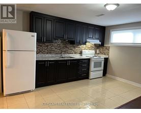 A kitchen with a white fridge and black cabinets.