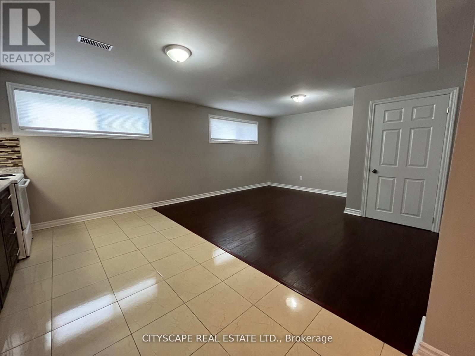 A spacious room with a white door and two windows.