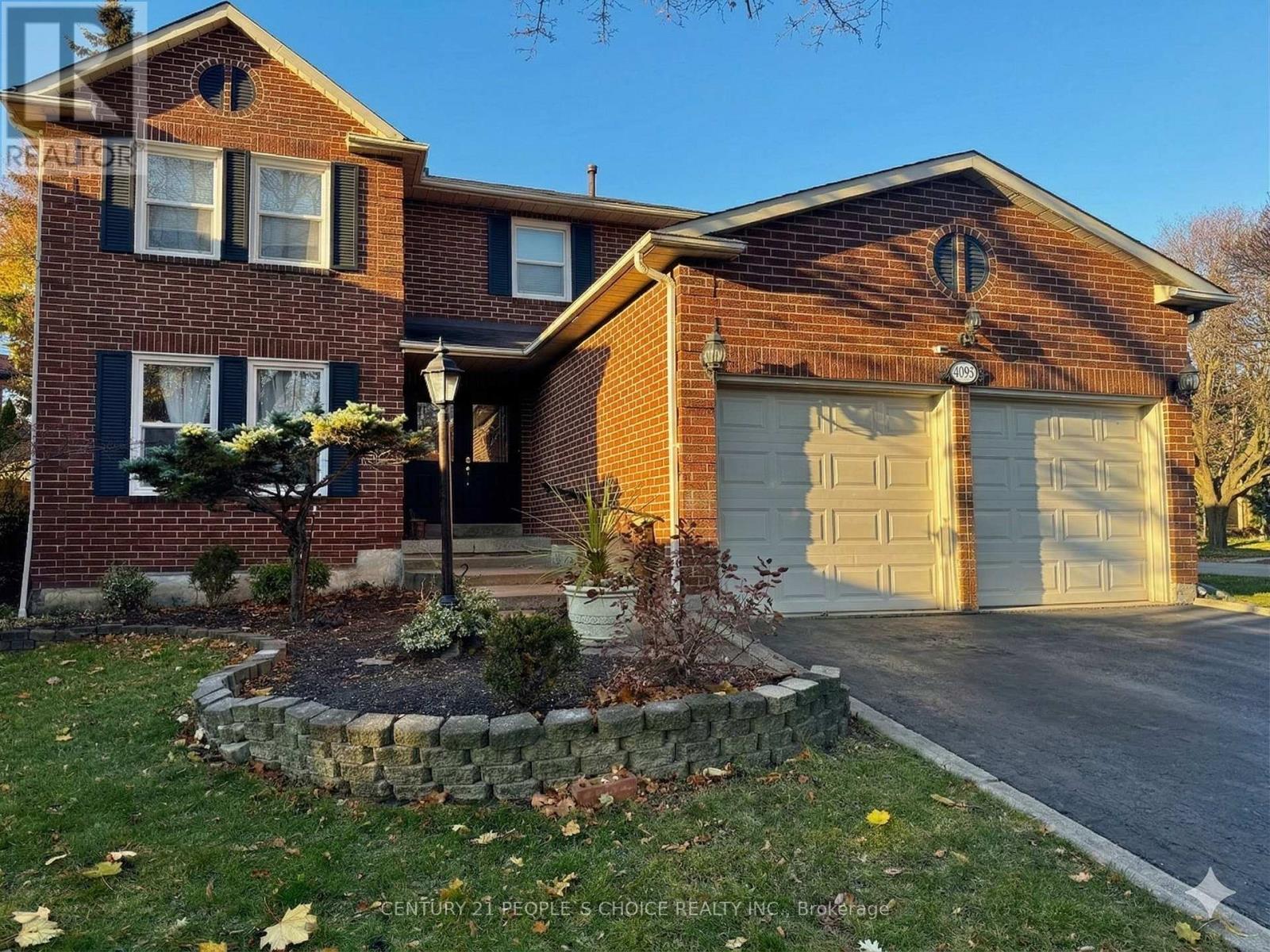 A brick house with a garage door and a stone wall in front.