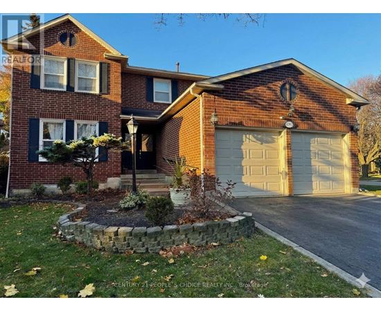A brick house with a garage door and a stone wall in front.