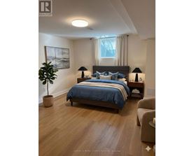 A bedroom with a bed, two lamps, a plant, and a painting on the wall.