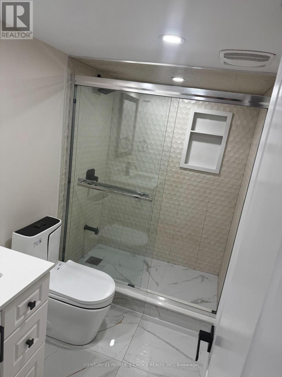 A white toilet sits in a bathroom with a glass shower door.