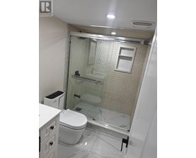 A white toilet sits in a bathroom with a glass shower door.