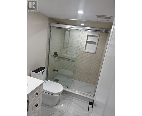A white toilet sits in a bathroom with a glass shower door.