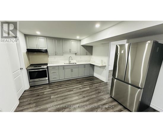 A modern kitchen with a stainless steel refrigerator and wooden flooring.