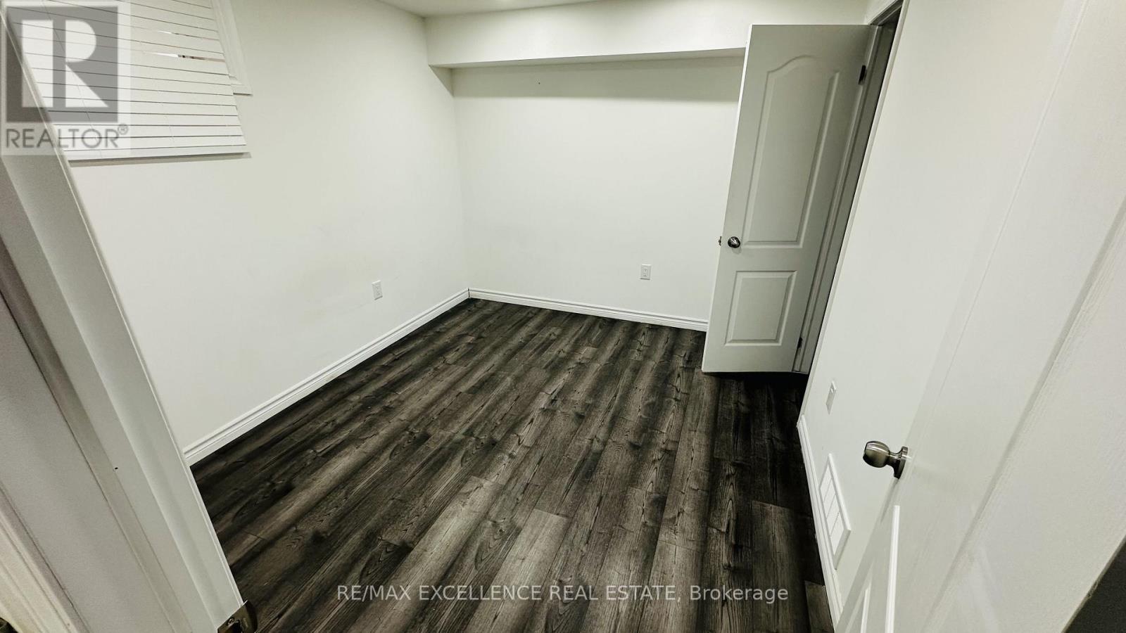 A room with wooden flooring and white walls.