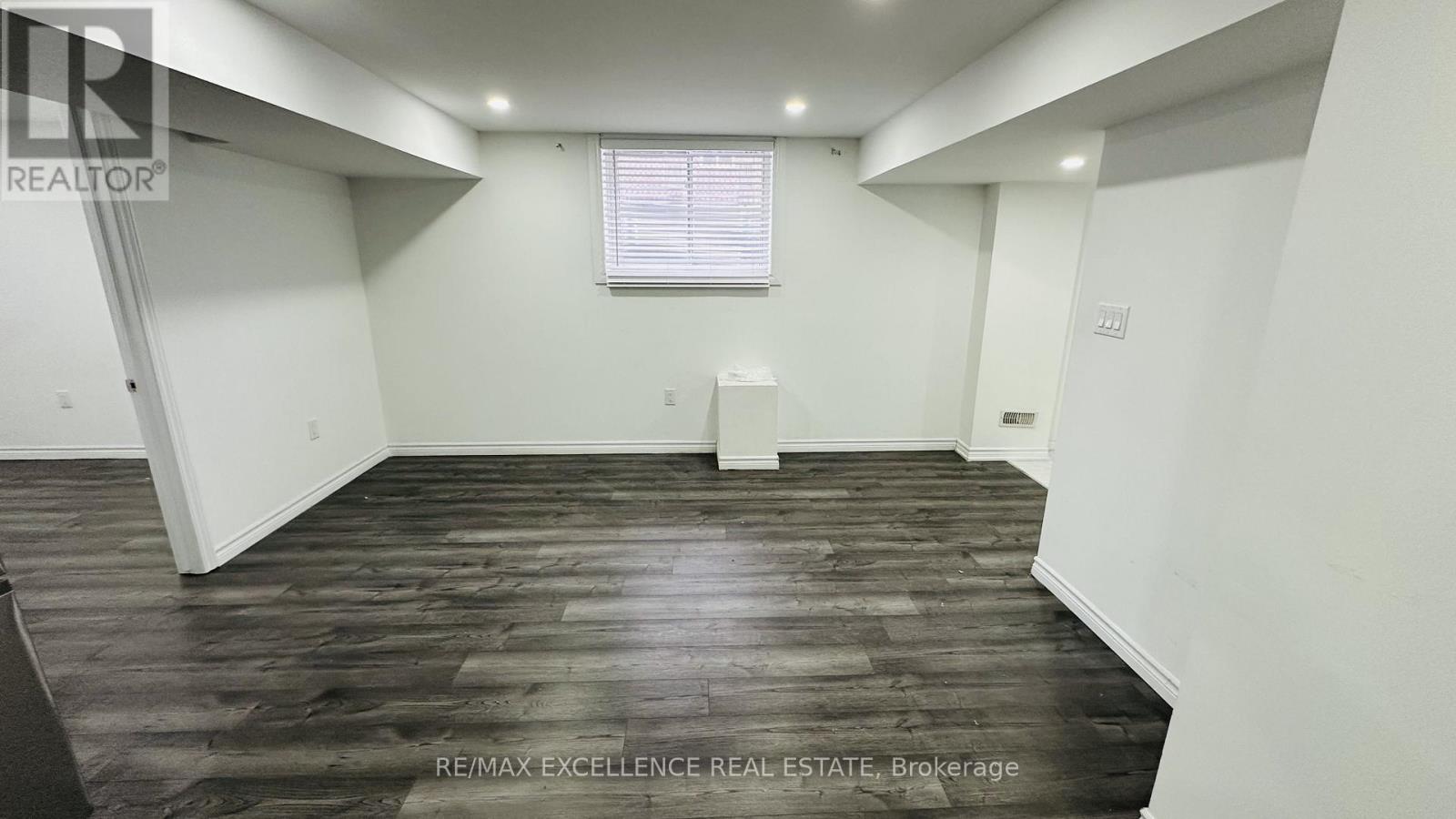 A spacious room with wooden flooring and white walls.
