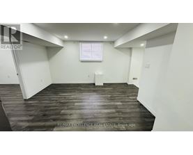 A spacious room with wooden flooring and white walls.