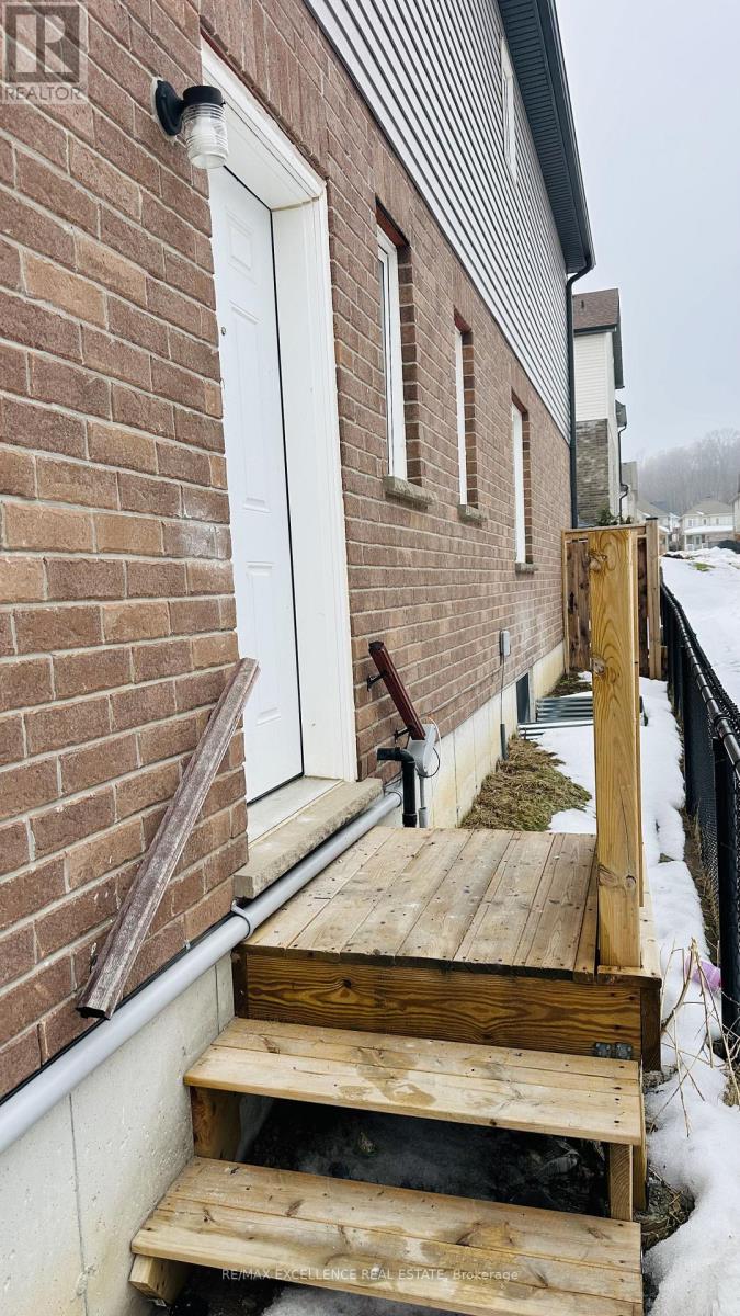 A wooden ramp leads up to a white door on a brick building.