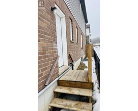 A wooden ramp leads up to a white door on a brick building.