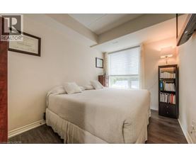 A bedroom with a bed, a bookshelf, and a window with blinds.