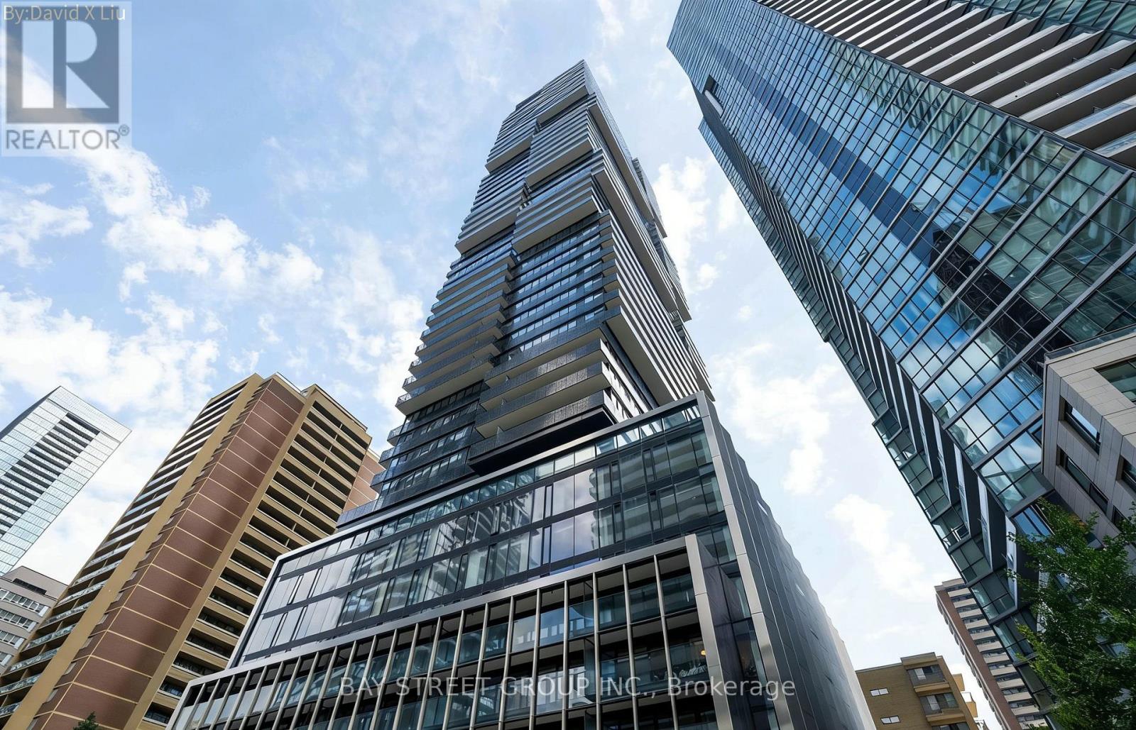 A tall skyscraper with the name "Bay Street Group Inc." on its facade stands among other buildings.