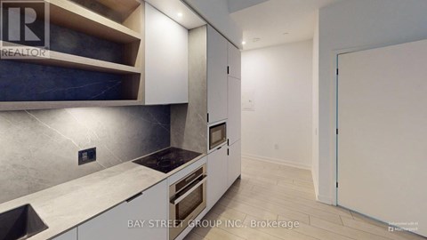 A modern kitchen with white cabinets and a stainless steel backsplash.